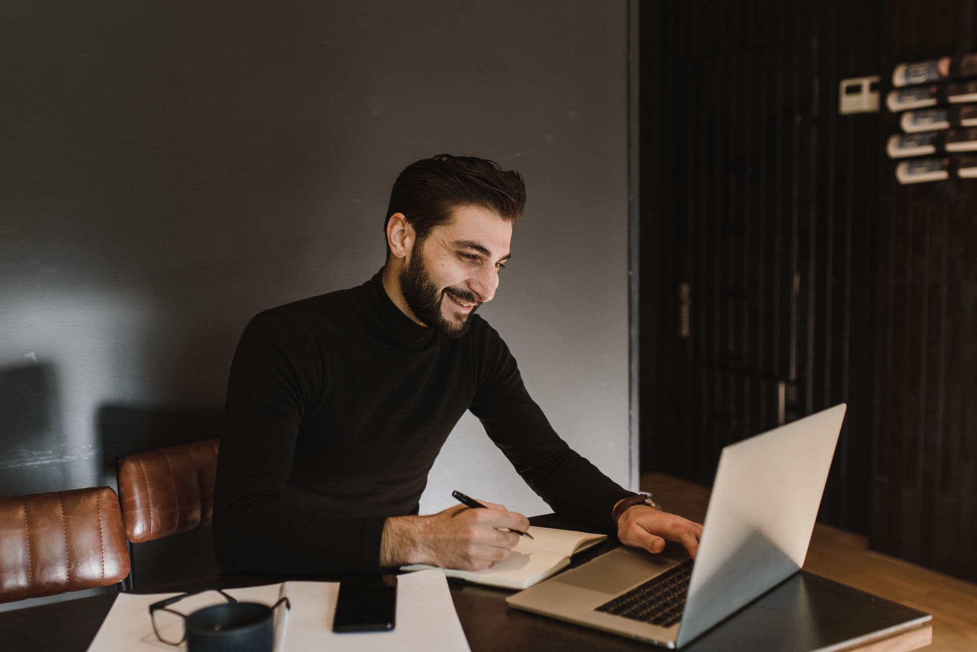 Ondernemer werkt lachend op zijn laptop